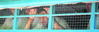 Suresh, Bablis brother, peers through the police van mesh outside the district courts in Karnal.