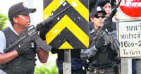 Thai police officers look for snipers as they clear any 