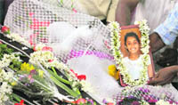 A mourner places a photograph among bouquets over the coffin of Air India Express crash victim H. Gloria during a service at the St. Alphonsa Catholic Church