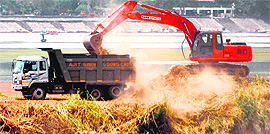 An earth mover dumps silt into a truck during the ongoing desilting drive at Sukhna Lake on Thursday.