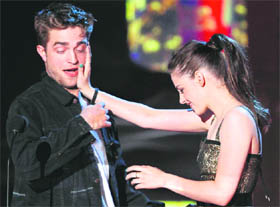Actors Robert Pattinson and Kristen Stewart (R) accept the award for Best Kiss as they attempt to kiss at the 2010 MTV Movie Awards in Los Angeles