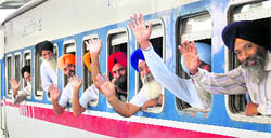 Sikh devotees wave as they leave in a special train for Pakistan to observe the martyrdom day of Guru Arjan Dev, at Amritsar railway station on Tuesday