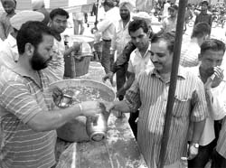 People distribute sweetened water at the district courts complex in Patiala on Saturday