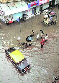 A taxi plies on a water-logged street after a heavy shower in Parel, Mumbai, on Wednesday.