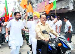 Minister for Jails Hira Singh Gabria rides pillion during the protest as BJP district president Rajiv Katna drives the motorcycle without a helmet