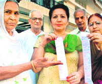 Residents of Phase VII, Mohali, show copies of electricity bills on Tuesday.