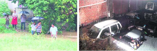 Residents cross a flooded stream at Nehru Gram and (right) submerged cars in a workshop in Dehradun on Saturday.