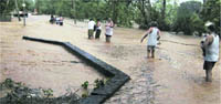 Residents use a rope to hold on as they come out of their flood-hit Urjani village in Yamunanagar district of Haryana