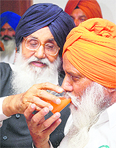 Punjab Chief Minister Parkash Singh Badal offers fruit juice to president of BKU at a press conference in Chandigarh on Friday. 