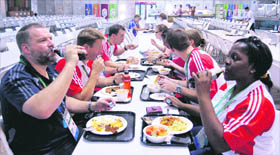 Members from Englands team for the Commonwealth Games eat food inside the food court of the athletes village in New Delhi on Saturday.