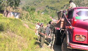 Security forces help villagers to shift their luggage.