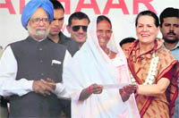 Prime Minister Manmohan Singh along with UPA chairperson Sonia Gandhi hands over the Unique Identification (UID) card to a tribal woman in Tembhali, Maharashtra,