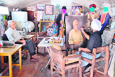 Painting a legend: The artist paints a portrait of Nek Chand, the creator of the Rock Garden, on location, in his office. — Photo by Roopinder Singh