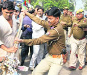 A cop in action as a BJP activist tries to burn PChidambarams effigy in Allahabad