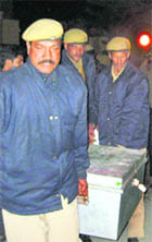Cops carry a box containing cash from the monastery at Sidhbari on Friday.