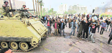 An Egyptian army armoured personnel carrier drives past anti-government protesters in Cairo on Saturday. Embattled Egyptian President Hosni Mubarak refused to bow to mounting pressure to quit even as nationwide demonstrations against his 30-year rule entered the fifth day.