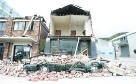 A car is seen crushed under debris after an earthquake in Christchurch