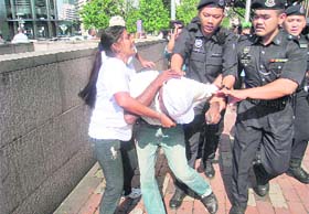 Policemen drag away a Hindu group activist in Kuala Lumpur