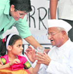 Anna Hazare accepts a glass of lemon water from a child to break his indefinite fast at Jantar Mantar in New Delhi