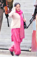 A woman walks past security persons guarding a street during a strike call to protest against the killing of cleric Showkat Ahmad Shah in Srinagar 