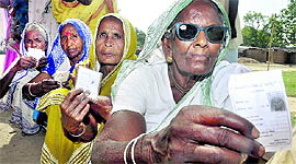 Voters show their identity cards as they wait to cast their votes at a polling booth on Saturday.
