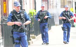 Armed police officers patrol a side street near Westminster Abbey ahead of the royal wedding in London