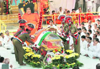 Police personnel place a Tricolour on Sathya Sai Babas casket during his funeral in Puttaparthi on Wednesday.