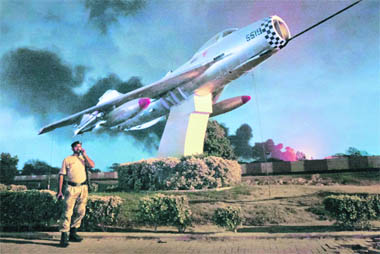 A plume of smoke rises from the background as a military official uses a phone at the entrance to the Mehran naval aviation base which was attacked by militants in Karachi.
