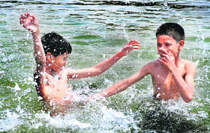 Two boys take a dip in the Sector 42 lake in Chandigarh on Monday following a rise in temperature