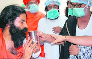 Baba Ramdev being offered juice by various Hindu religious leaders at the Himalayan Hospital 