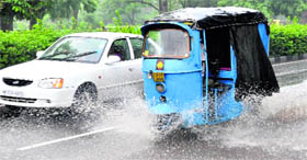 A car and an autorickshaw try to outpace each other on a rainy morning at Madhaya Marg in Chandigarh on Friday.