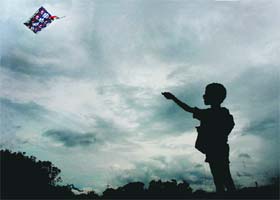 A child flies a kite, with dark clouds forming the backdrop, in Chandigarh on Wednesday