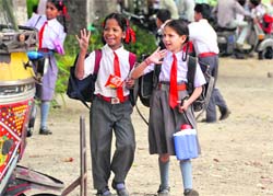 Two girls all smiles on returning home from school in Ludhiana. Government schools re-opened after summer vacation