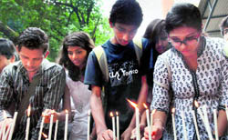 Students light candles to pay homage to the victims of the recent serial blasts, in Mumbai on Saturday.