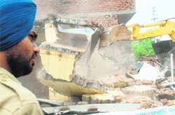 A JCB razes an illegal structure at Madanpura village in Mohali