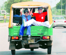 Schoolchildren hang out precariously from an auto-rickshaw on the Chandigarh-Panchkula road on Friday