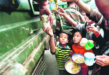 Children gather around an Army truck distributing food in Gangtok on Tuesday. The biggest challenge before officials now is to reach the worst-hit areas. 