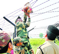 BSF men retrieve a bag of heroin stuck on the border fence at Rajatal village on Thursday