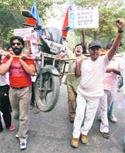 Demonstrators carry a motorbike with the help of bamboo sticks to protest a hike in petrol prices in New Delhi on Friday.