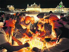 Devotees light candles on the occasion of the 542nd birth anniversary of Guru Nanak Dev at the Golden Temple in Amritsar on Thursday. 