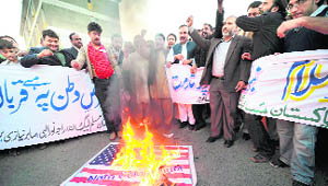 Pakistanis shout slogans in front of a burning US flag  in Islamabad on Wednesday. 