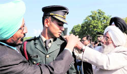 The father and grandfather of a Gentleman Cadet of the Indian Military Academy remove the strap to show his official insignia known as “Pipping Ceremony” after the parade at the academy in Dehradun on Saturday