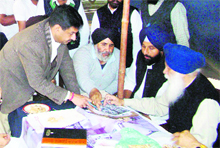 Moga SSP Snehdeep Sharma (left) shows the plan for the SAD rally to Youth Akali Dal president Bikramjit Majithia and others at Kili Chahal village in Moga district