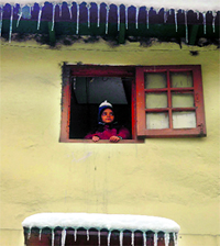 A child gazes from his window with icicles hanging from the roof of a house in Shimla on Tuesday.