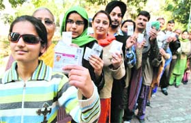 People stand in a queue for casting their vote at a polling station in Patiala on Monday