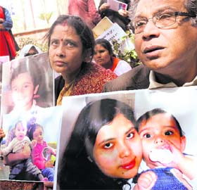 Sikha (L) and Monotosh Chakrabarty hold portraits of their grandchildren outside the Norwegian Embassy in New Delhi on Monday