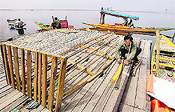 A boatman repairs his shikara on the banks of the Dal Lake