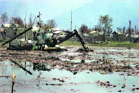A weed harvester plucks out unwanted underwater growth in Dal Lake in Srinagar