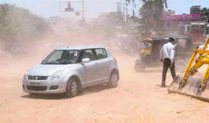 A car passes through a dusty area near the airport traffic lights as sewerage work goes on