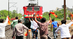BJP activists run towards a train to block its way during a protest against petrol price hike in Ahmedabad.